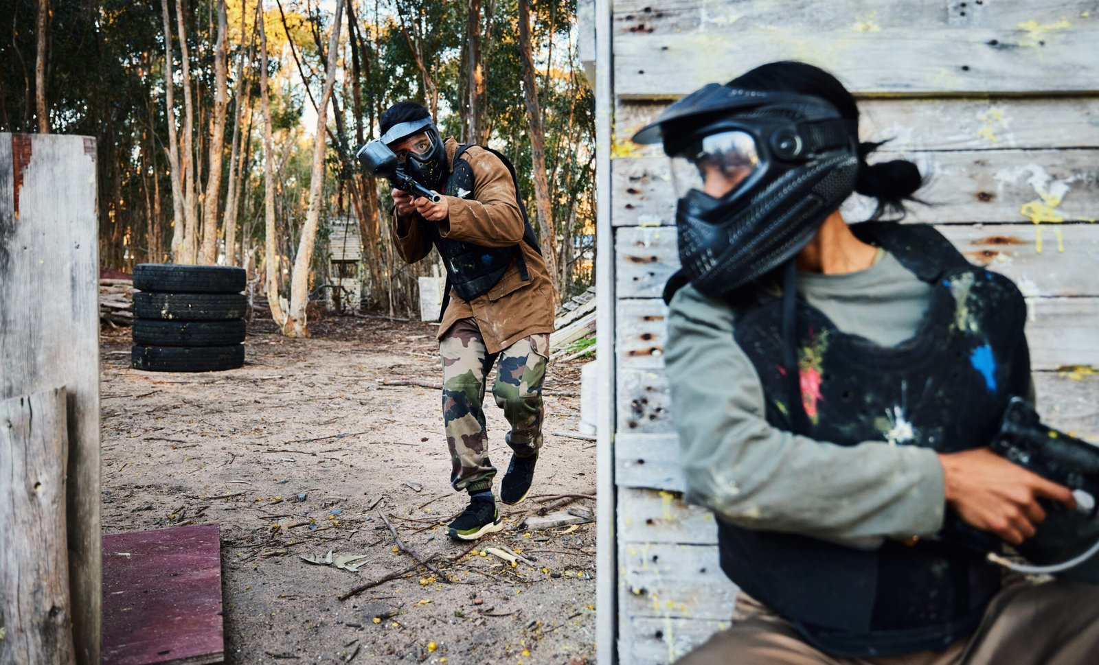 Paintball, sports and man with gun for battle, game or competition outdoors on field. War fight, military army and male soldier with weapon on shooting range while hiding from opponent for exercise